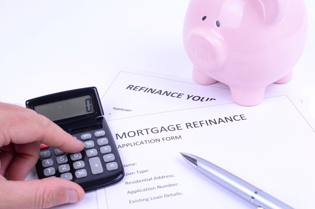mortgage refinance document with calculator and piggy bank